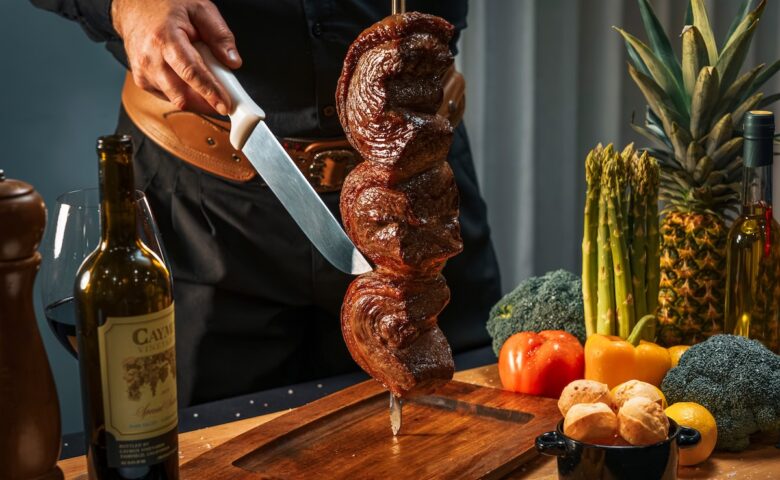 person cutting meat on a stick