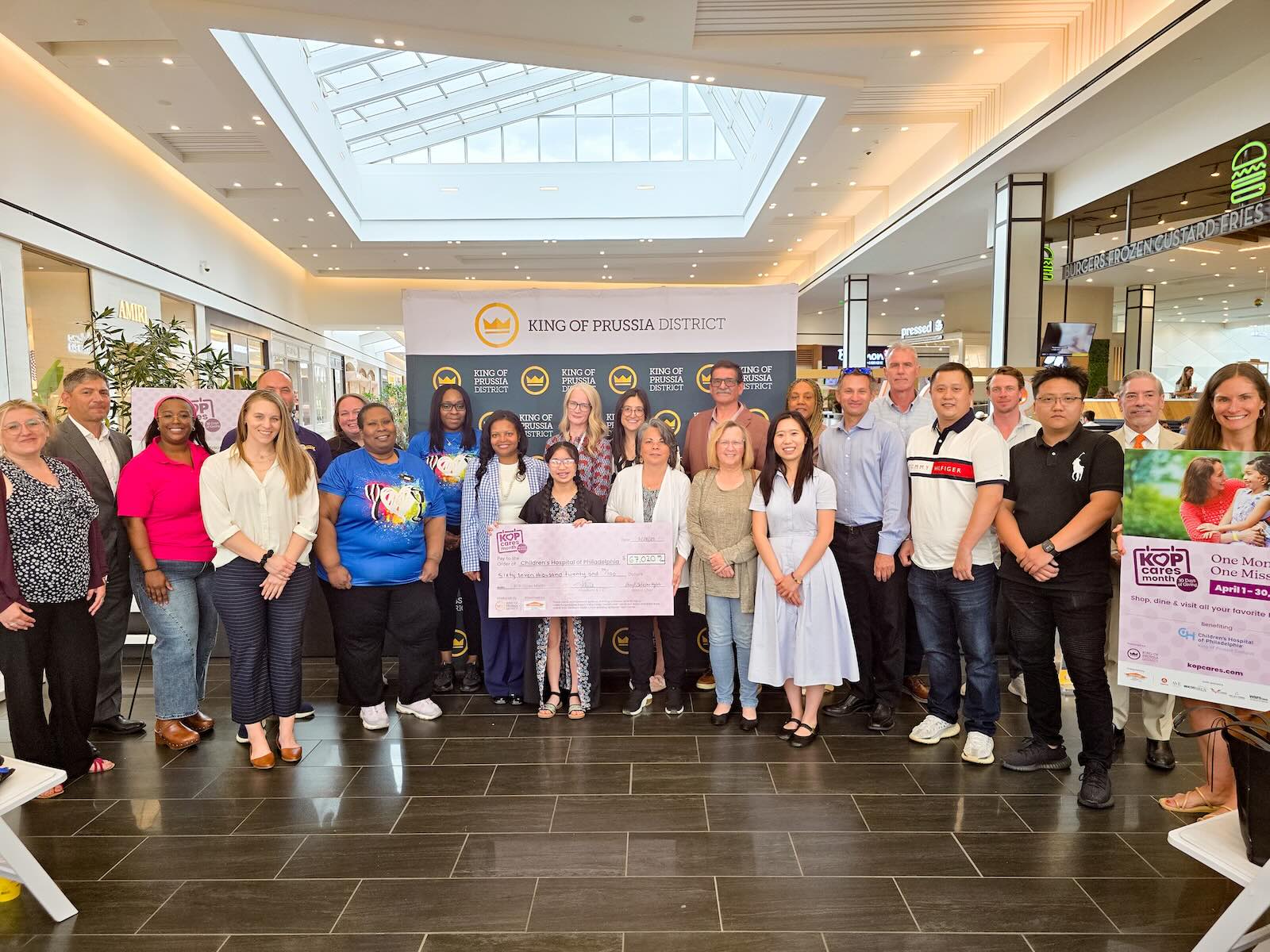 group of people posed around a large check