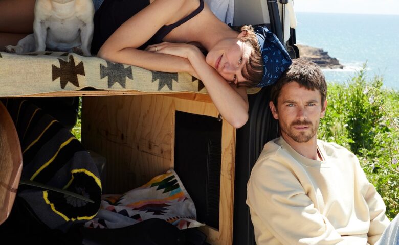 Two people in back of van with a french bulldog