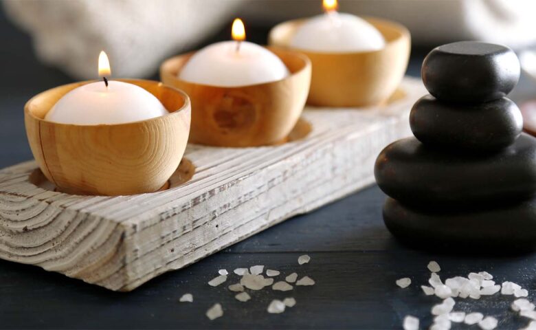 candles in a holder and stones on a black surface